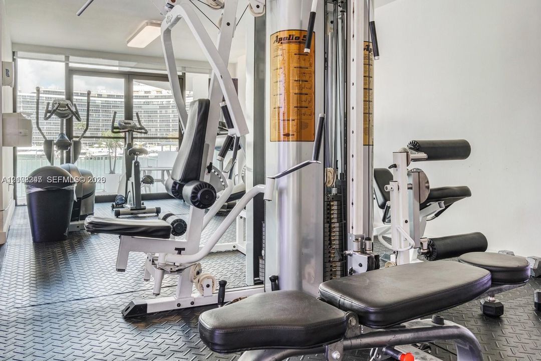 Fitness center featuring black diamond-plate rubber flooring and floor-to-ceiling glass sliding doors
