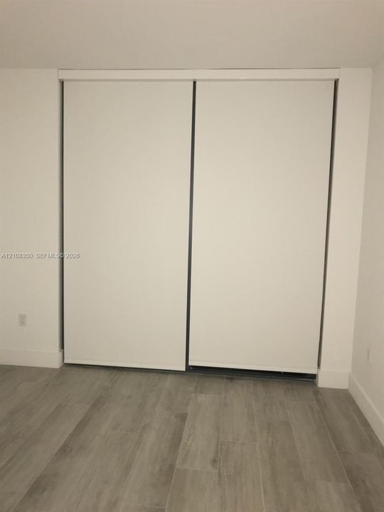 Sliding closet with white panel doors and wood-finish flooring