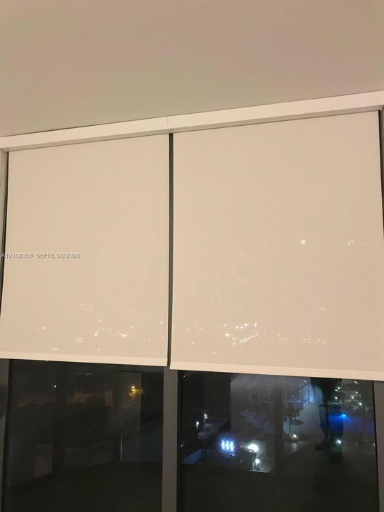 Floor-to-ceiling windows featuring dual-pane glazing, dark-finish metal frames, and integrated retractable roller shades