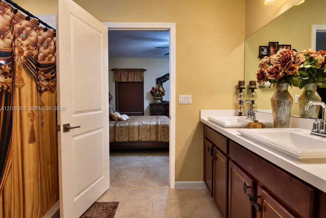 Dual-sink vanity with rectangular vessel sinks, white countertop, dark wood cabinetry, and large-format wall mirror
