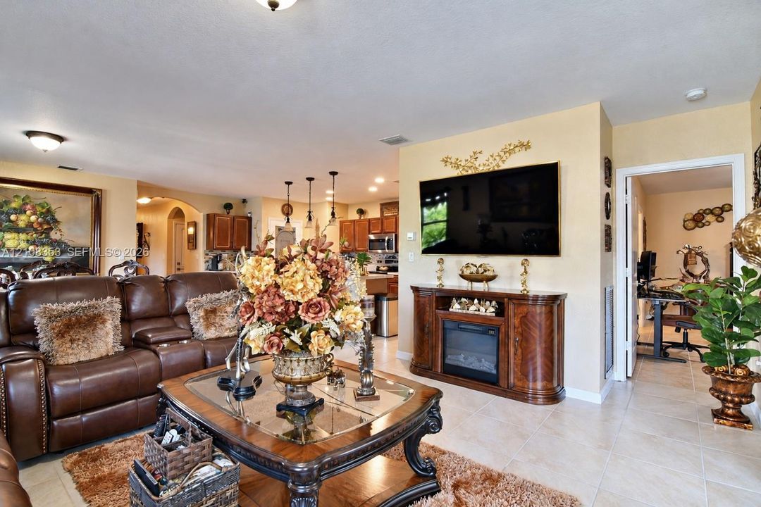 Open-concept area featuring neutral wall tones, large-format tile flooring, recessed ceiling lighting, and a built-in media console with an integrated electric fireplace