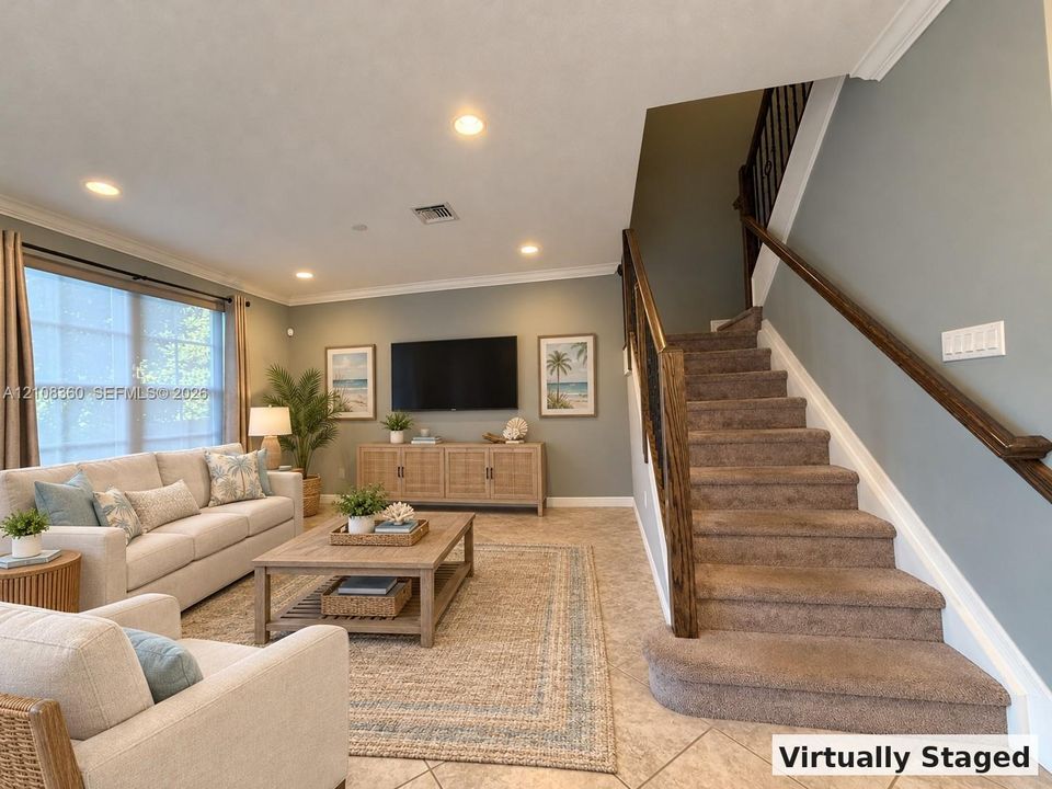 Open-concept interior featuring large-format tile flooring, recessed lighting, crown molding, and a staircase with stained wood handrails and metal balusters