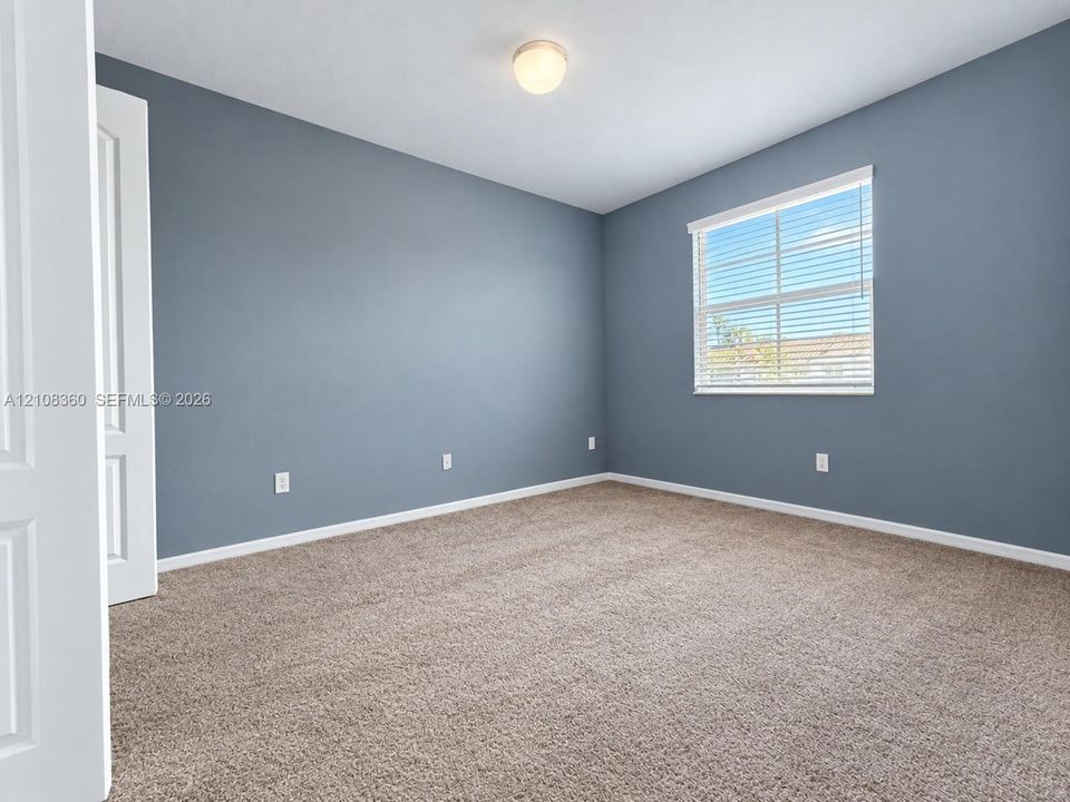 Neutral-toned walls, wall-to-wall carpeting, single-hung window with blinds, flush-mount ceiling light fixture, and six-panel interior door