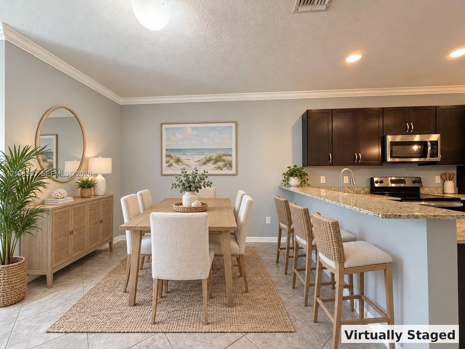 Kitchen featuring dark cabinetry, stone-surface breakfast bar, and stainless steel appliances, complemented by tile flooring and crown molding