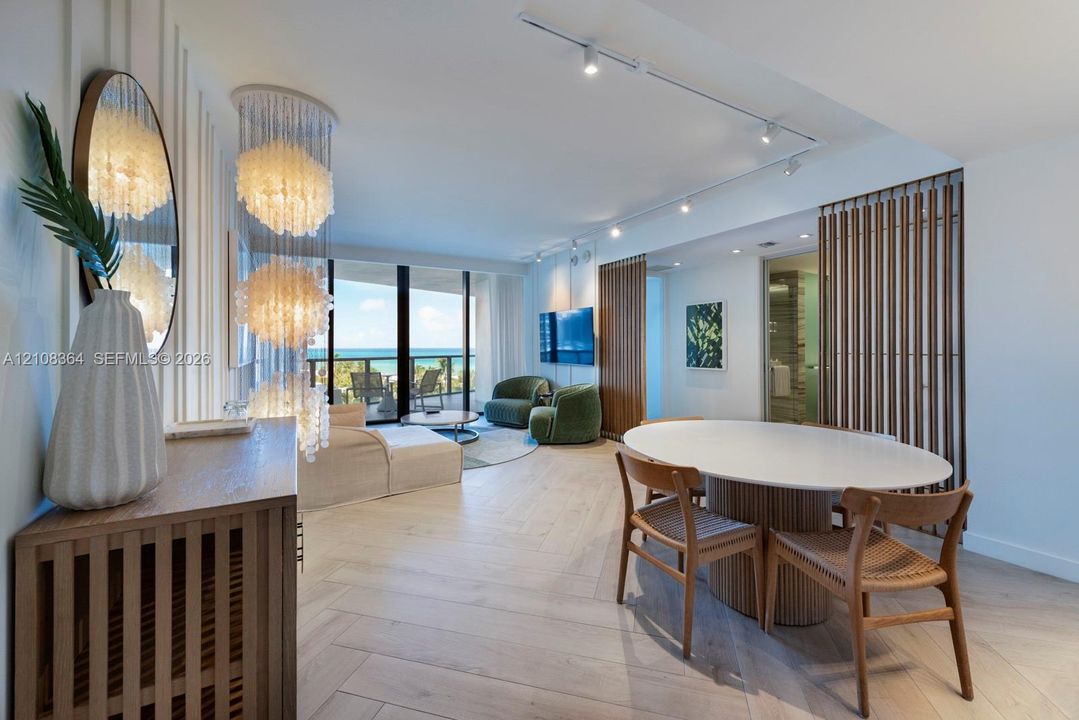 Herringbone wood-finish flooring, floor-to-ceiling glass balcony doors, decorative tiered pendant lighting, vertical wood slat wall detailing, and adjustable track lighting