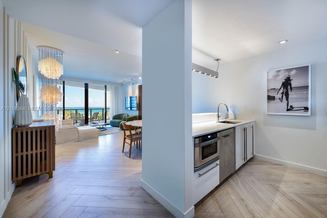 Herringbone wood-finish flooring, white flat-panel cabinetry, integrated stainless steel microwave, quartz countertops, and floor-to-ceiling glass sliding doors