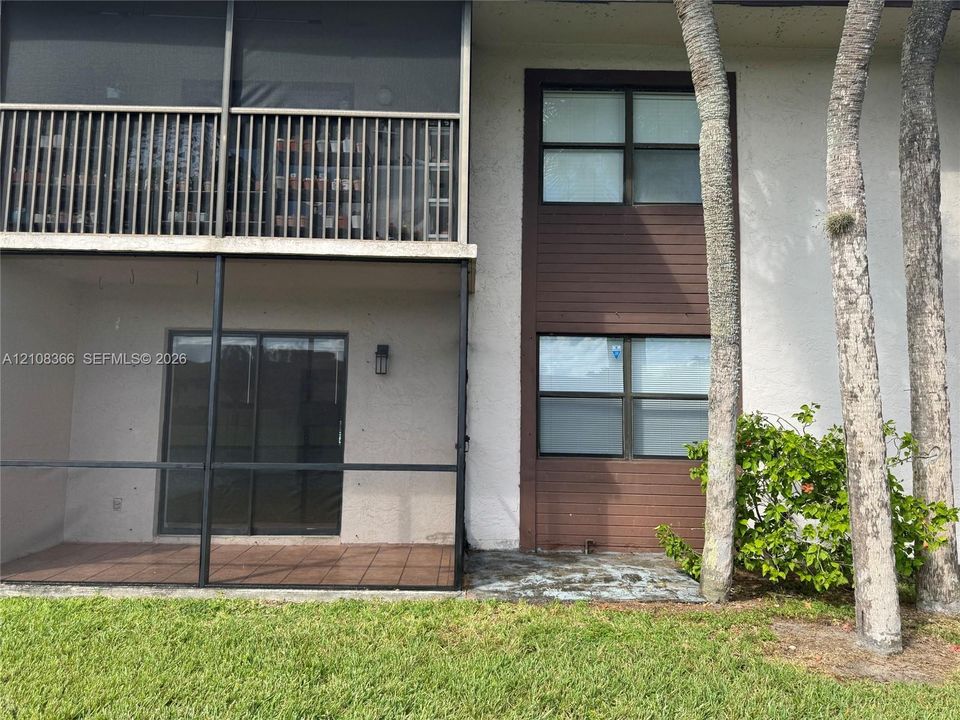 Stucco exterior featuring dual-level screened lanais, sliding glass entry doors, and wood-paneled accents surrounding multi-pane windows