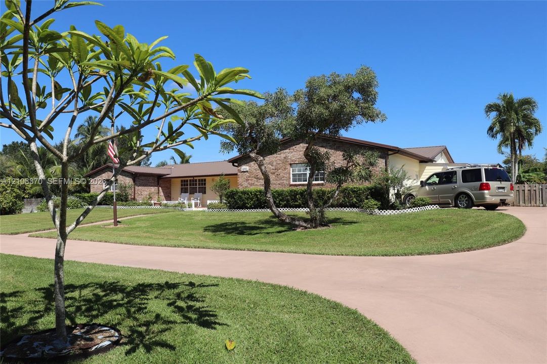 Single-story residence featuring a brick and siding exterior, expansive lawn, mature landscaping, and a concrete driveway