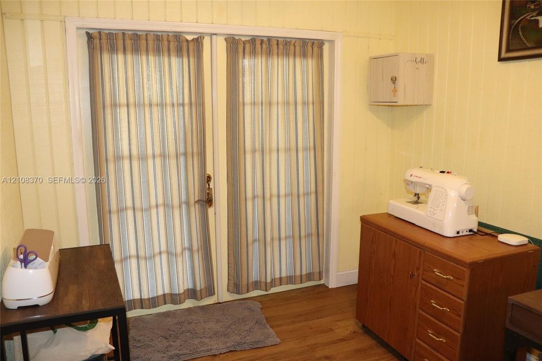 French doors featuring multi-lite glass panels, vertical paneled wall treatments, and wood-finish flooring