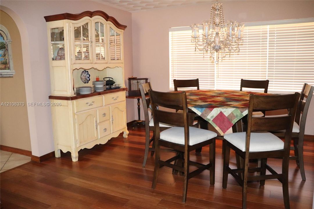 Wood-finish flooring, crystal-style chandelier, and an arched wall opening