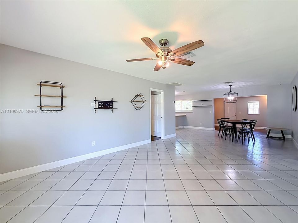 Large format ceramic tile flooring, neutral wall tones, multi-blade ceiling fan with integrated lighting, and geometric wall-mounted shelving units