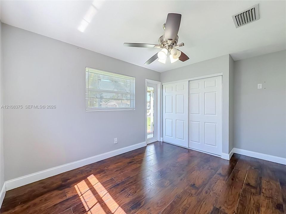 Room featuring wood-finish flooring, a ceiling fan with integrated lighting, a sliding closet with paneled doors, and a glass-paneled exterior door