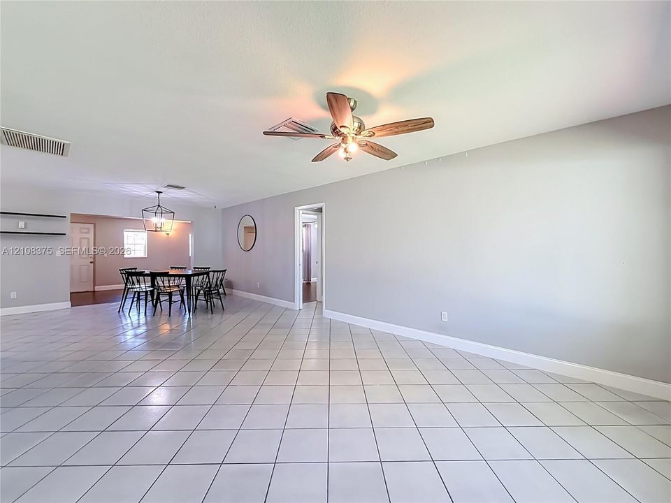 Large living area featuring neutral-toned tile flooring, recessed lighting, and a ceiling fan with integrated lighting