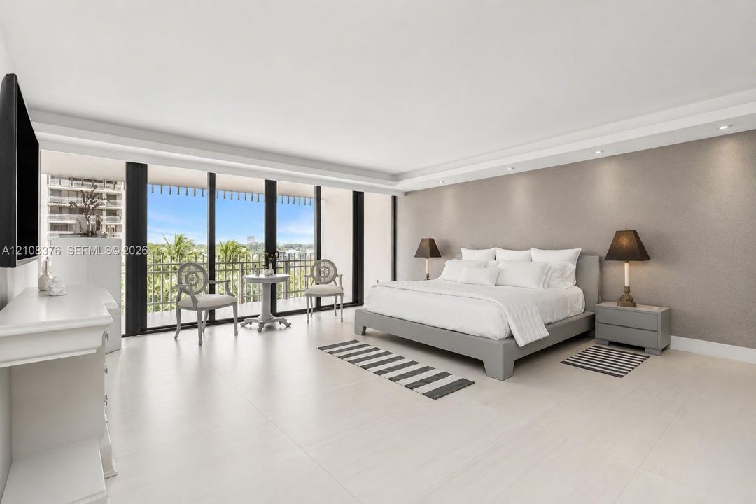 Large-format tile flooring, recessed ceiling lighting, crown molding, and floor-to-ceiling glass sliding doors opening to a covered balcony