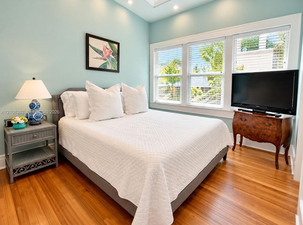 Wood-finish flooring, recessed ceiling lighting, and expansive triple-window configuration with white trim