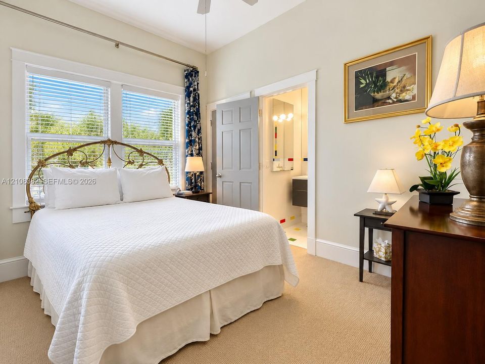 Bedroom featuring neutral wall color, plush carpeting, high ceilings with a mounted fan, and large windows with multi-pane glass