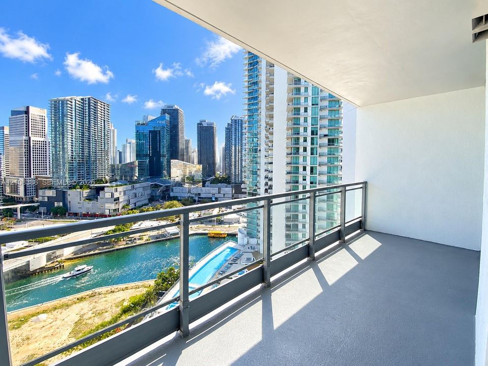 Private balcony featuring concrete flooring, a metal and glass railing, and urban scenery