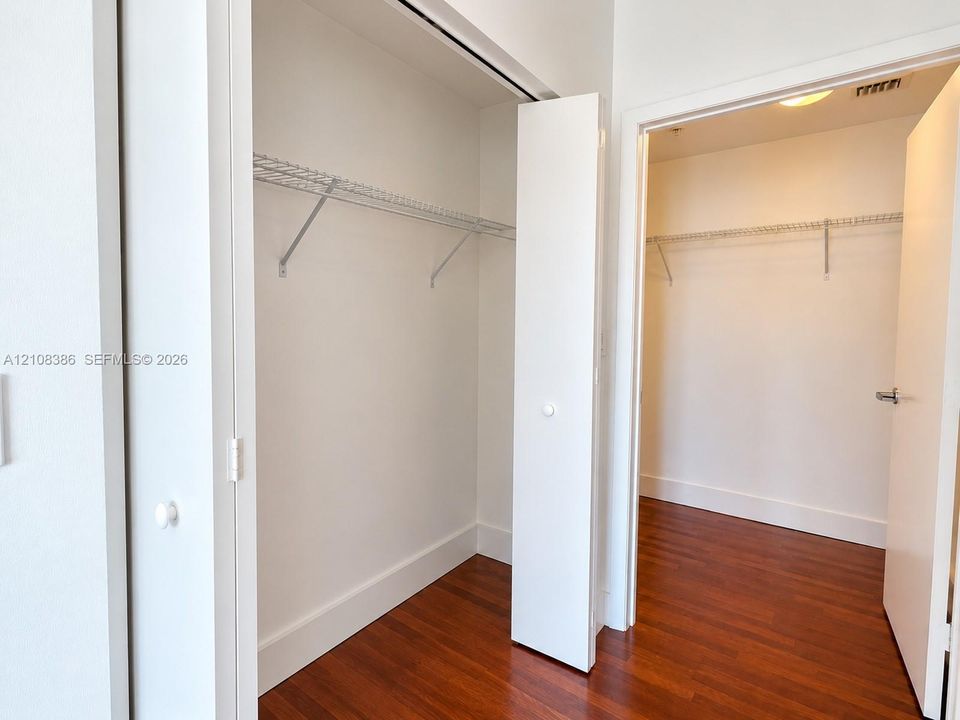 Storage space featuring wood-finish flooring, white doors, and installed wire shelving