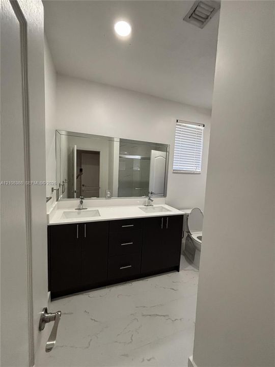 Bathroom featuring a pedestal sink, wall-mounted light fixture, framed mirror, and tile flooring
