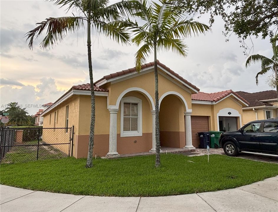 Exterior featuring a tiled roof, arched entryway with columns, two-tone stucco facade, and attached garage