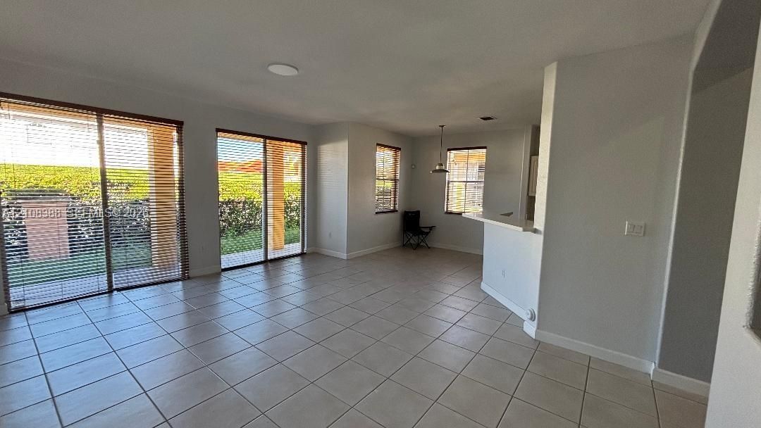 Interior room featuring wood-finish flooring, a tray ceiling, three large windows with blinds, and a two-panel interior door