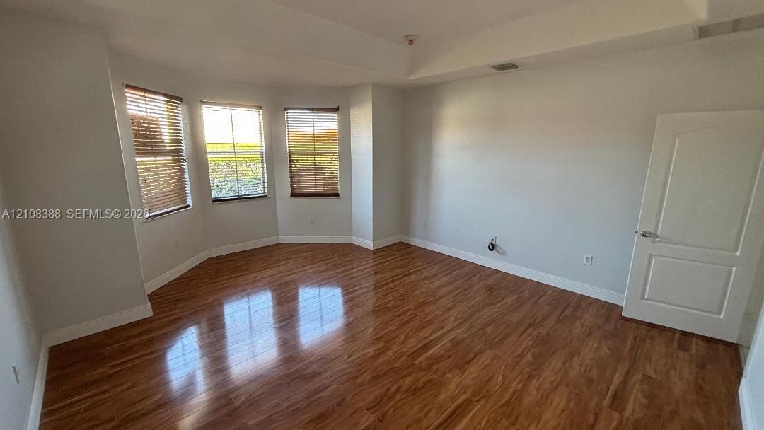 Room featuring tray ceilings, recessed lighting, and wood-finish flooring