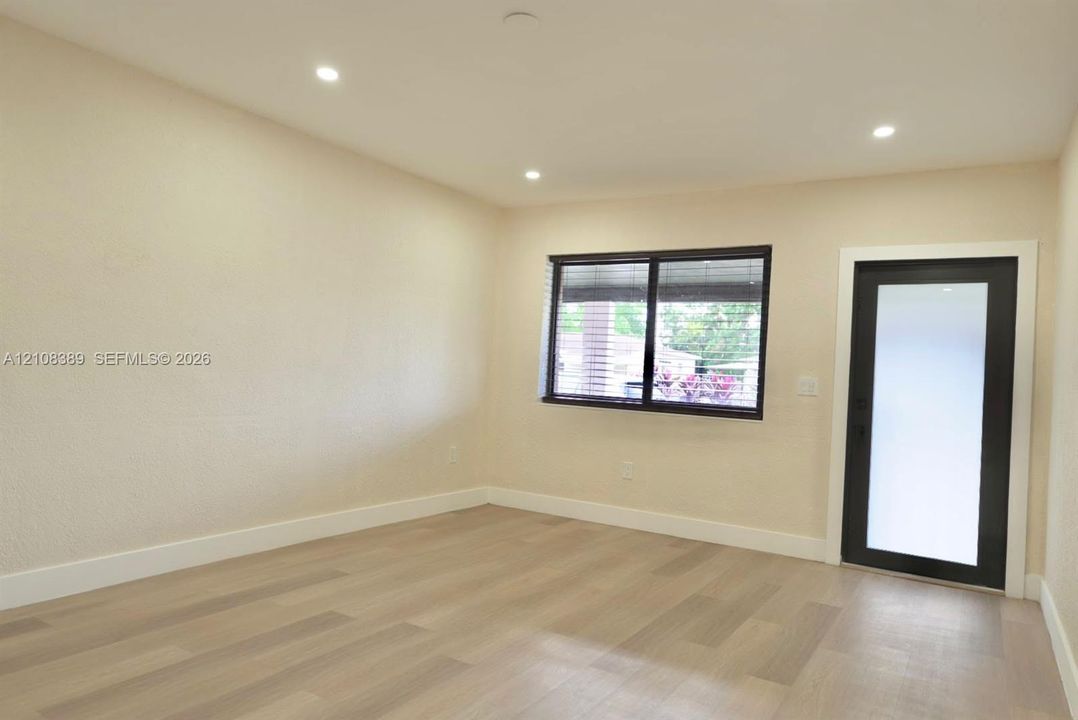 Interior space featuring wood-finish flooring, recessed lighting, textured walls, a single-pane window with dark trim, and a glass-paneled exterior door