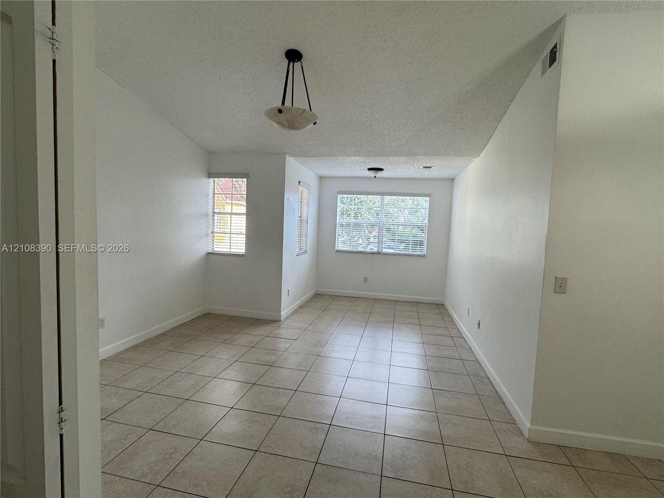 Vaulted ceilings featuring pendant lighting, ceramic tile flooring, and multiple windows with integrated blinds