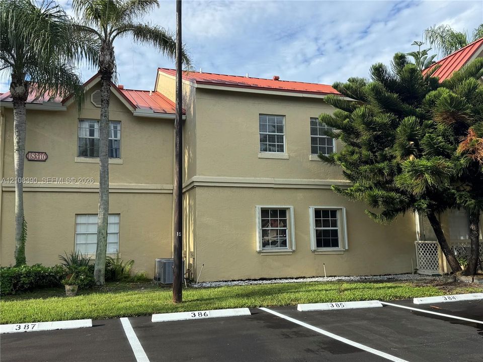 Two-story exterior featuring a metal roof, stucco siding, and double-hung windows