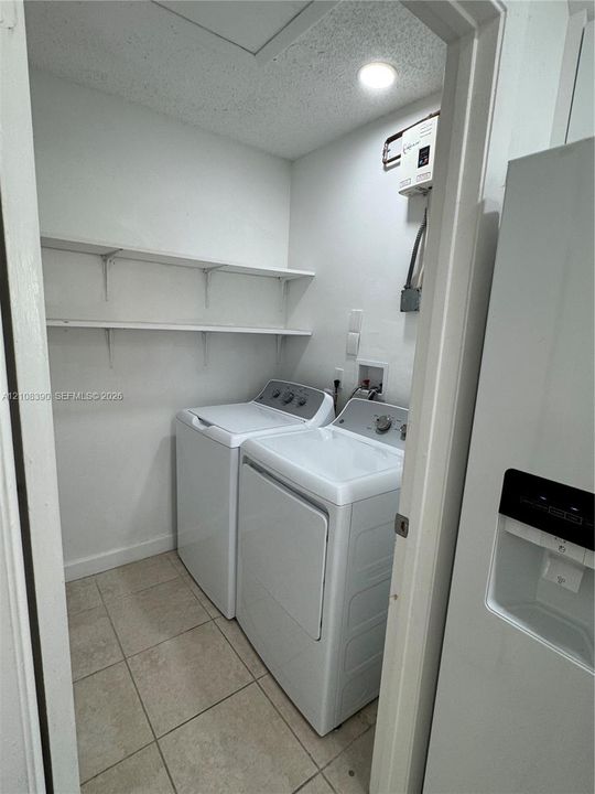 Laundry closet featuring tile flooring, built-in shelving, and dedicated hookups for a washer and dryer