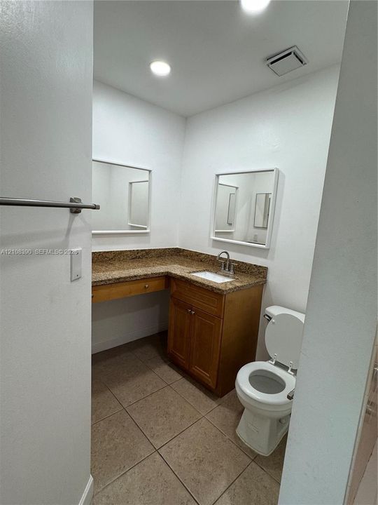 Bathroom featuring wood cabinetry, stone-finish countertop with an integrated basin, recessed lighting, and tile flooring