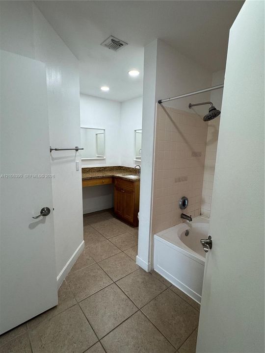 Bathroom featuring tiled flooring, a built-in vanity with stone countertop, recessed lighting, and a bathtub with a tiled surround