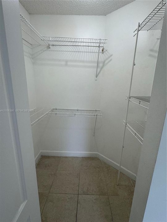 Walk-in storage space featuring ceramic tile flooring and multi-level wire shelving