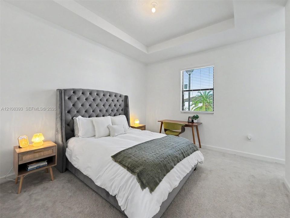 Tray ceiling, neutral carpet flooring, and single-hung window with horizontal blinds