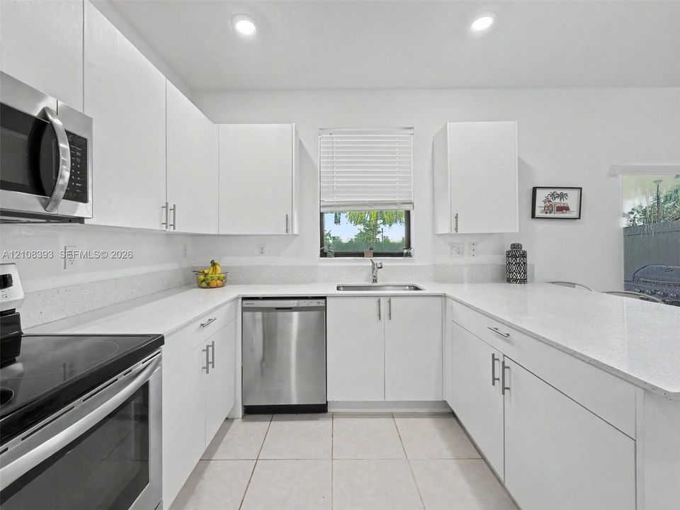 Kitchen featuring white cabinetry, solid-surface countertops, recessed lighting, and stainless steel appliances
