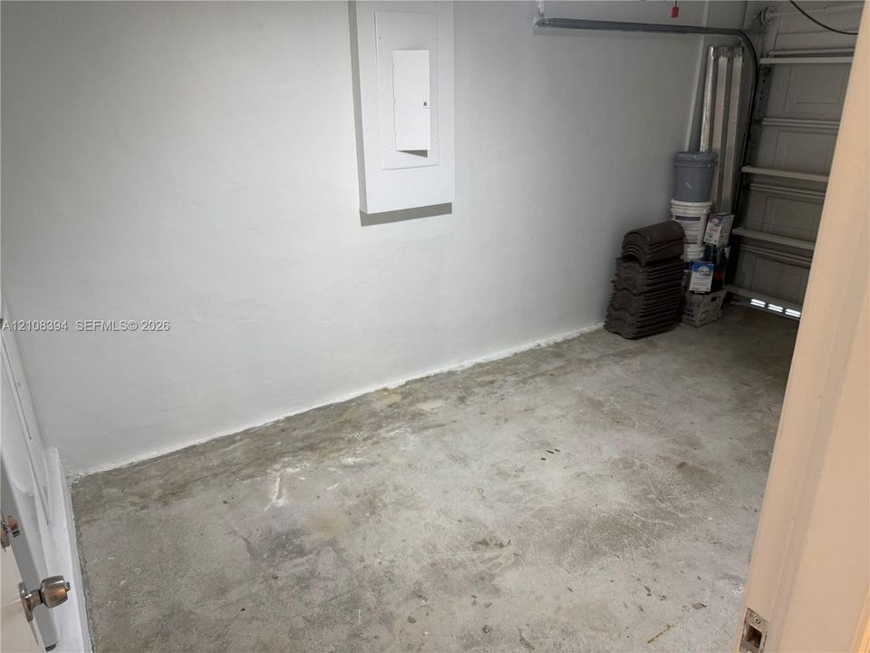Enclosed storage area featuring concrete flooring, smooth wall finish, and an integrated electrical panel