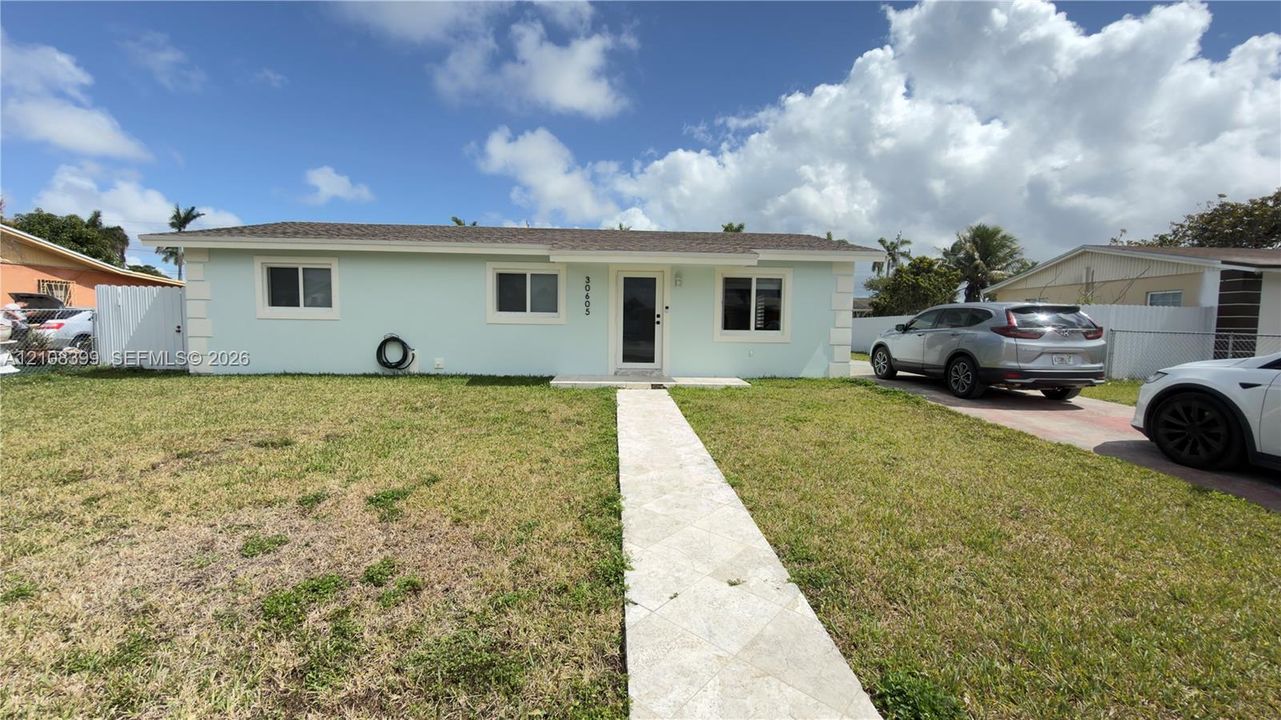 Single-story residence featuring a light-toned exterior, concrete tile roofing, stone-tiled front walkway, and white privacy fencing