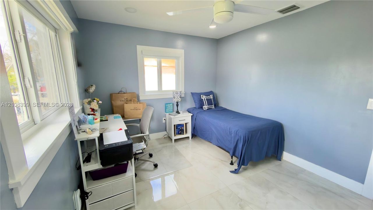 Neutral-toned tile flooring, white-cased dual-pane windows, and a ceiling-mounted fan with integrated lighting