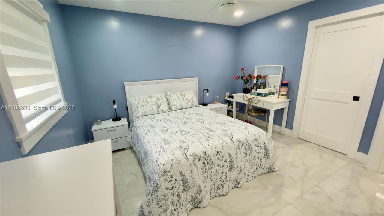 Bright room featuring light-toned tile flooring, dual-pane windows with integrated blinds, and a white two-panel interior door with matte black hardware
