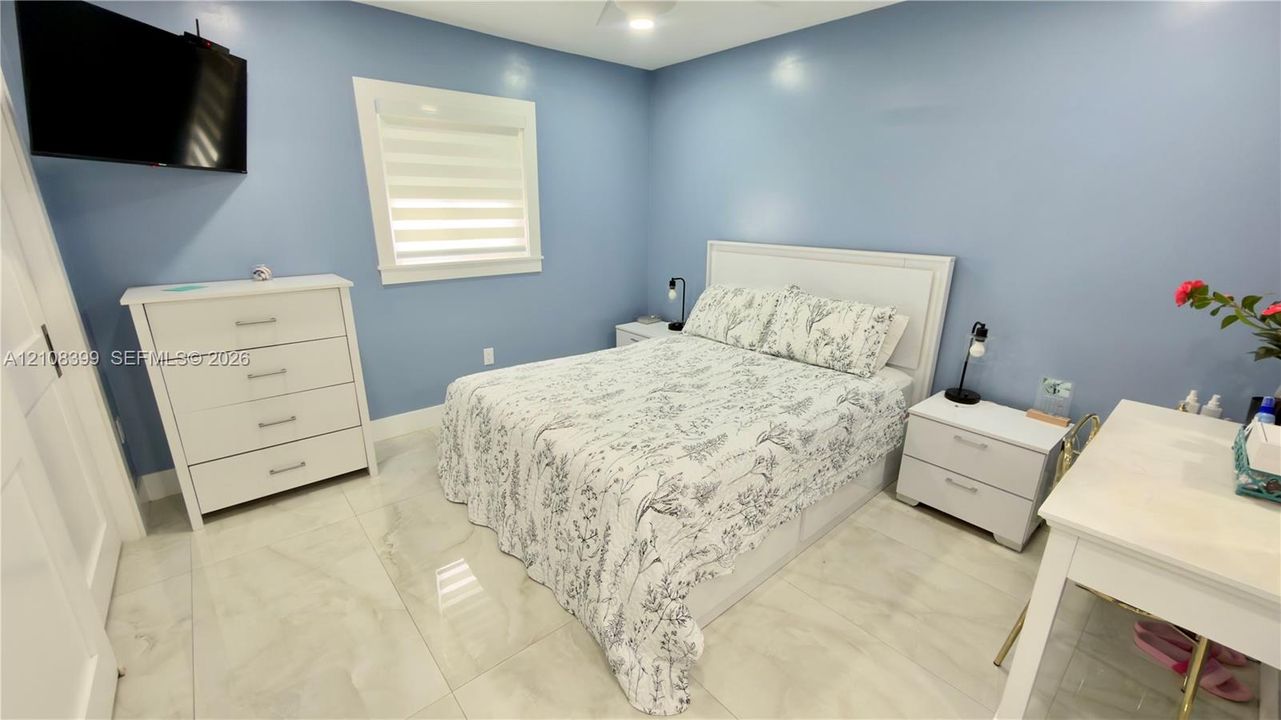Large-format tile flooring, light-toned wall finish, and a window with integrated dual-layer shade