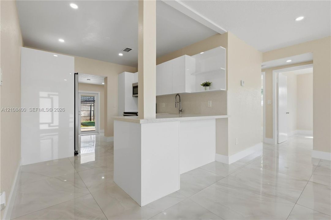 Kitchen featuring high-gloss white cabinetry, white stone countertops, polished tile flooring, and recessed ceiling lighting