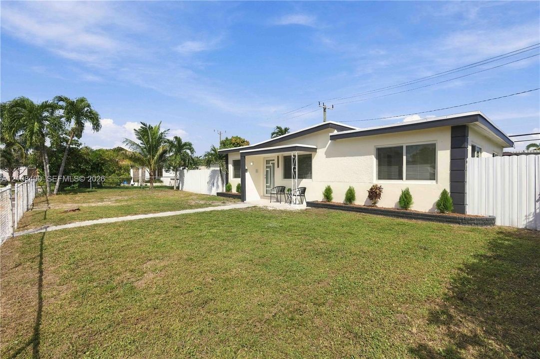 Single-story exterior featuring a light-toned textured facade, horizontal sliding windows, metal-post entryway canopy, and a fenced yard with perimeter landscaping