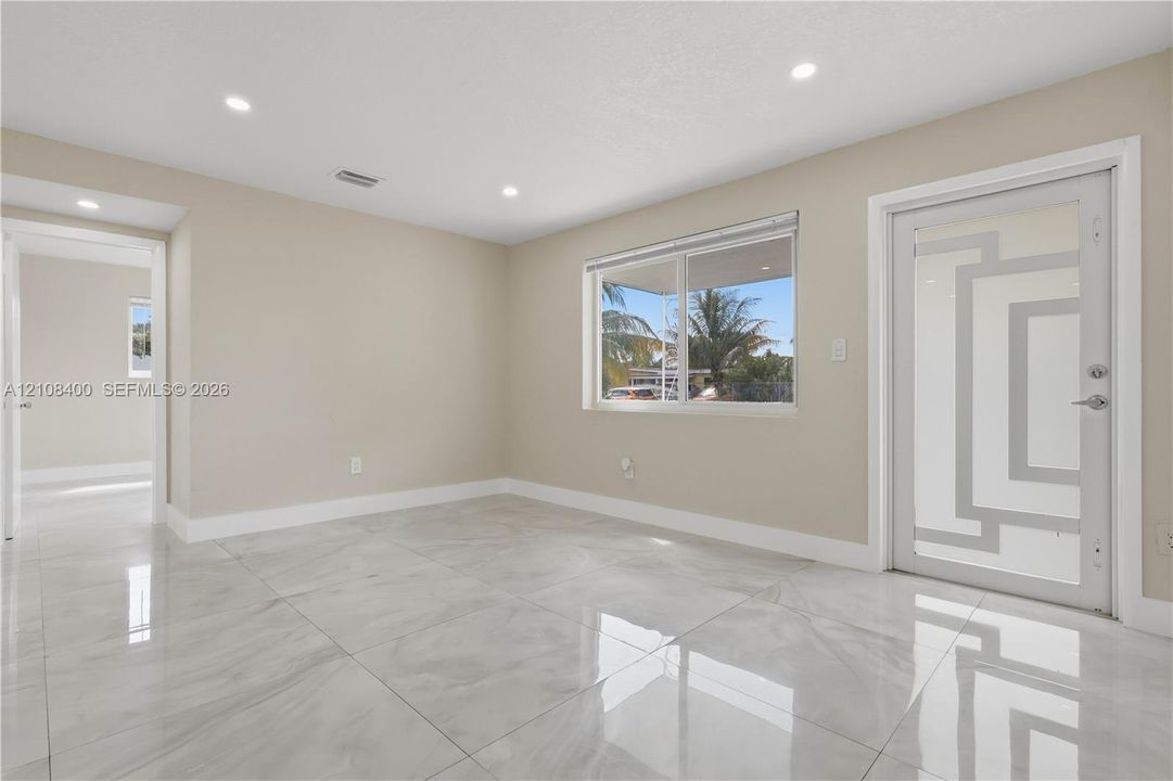Polished stone-finish flooring, recessed ceiling lighting, and exterior door with decorative glass insert