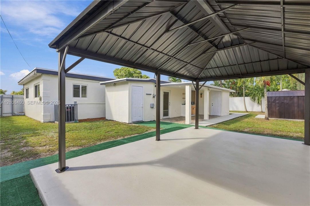 Covered metal-roofed patio with concrete flooring, open-air structure, and fenced backyard