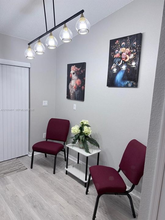 Five-light linear pendant fixture with glass shades, wood-finish flooring, and vertical-panel sliding door