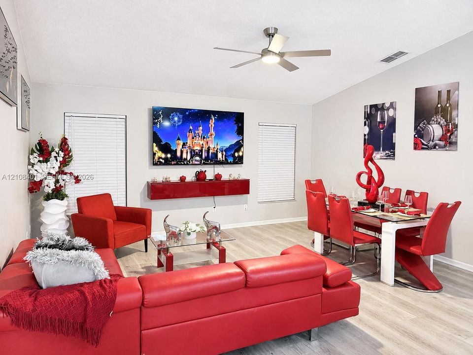 Open-concept living space featuring wood-finish flooring, a wall-mounted floating cabinet, recessed lighting, and a ceiling fan with integrated light