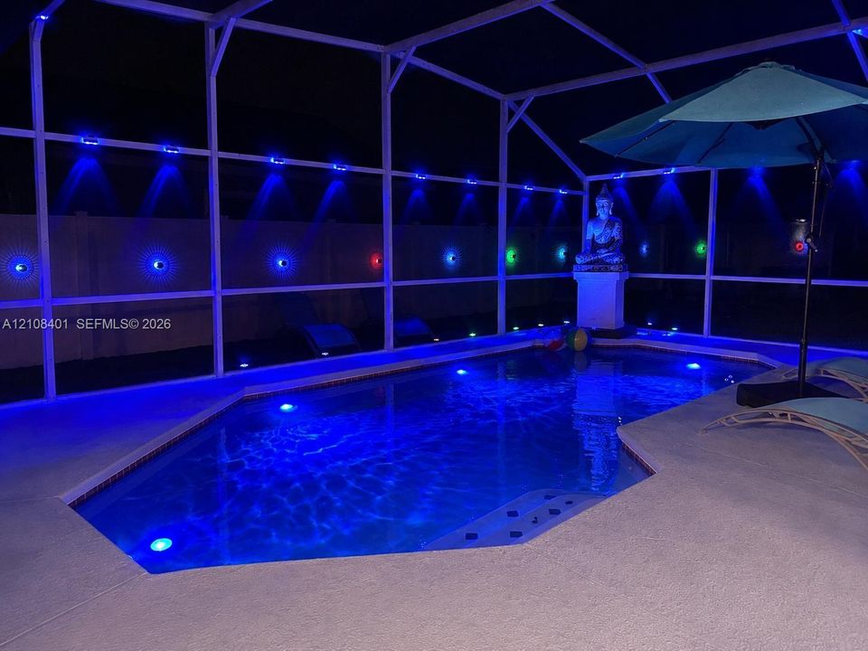 Screened-in pool area featuring a concrete deck and integrated accent lighting
