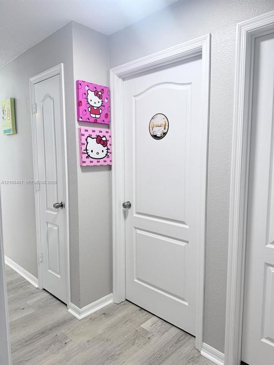 Hallway featuring two-panel interior doors, brushed metal hardware, and wood-finish flooring