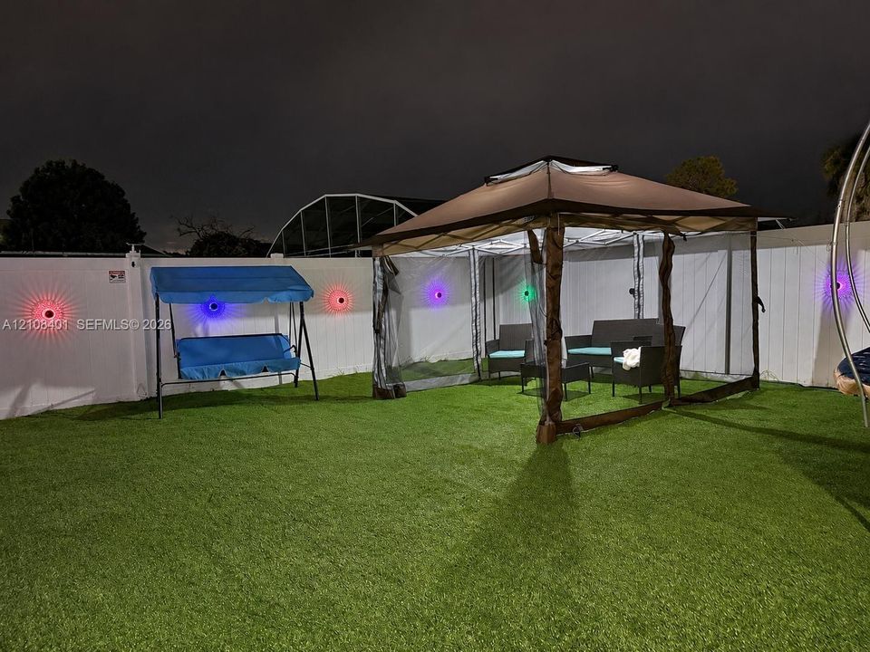 Backyard featuring synthetic turf and a full-perimeter white vinyl privacy fence