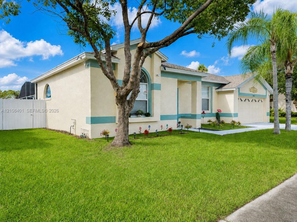 Stucco exterior featuring arched windows, a multi-car garage, and established landscaping
